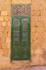 Malta, Birgu. Green shuttered door on stone wall. Art Print